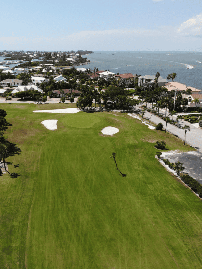 Panoramic view of a coastal golf course with lush green fairways, sand traps, and ocean backdrop, perfect for golf enthusiasts.