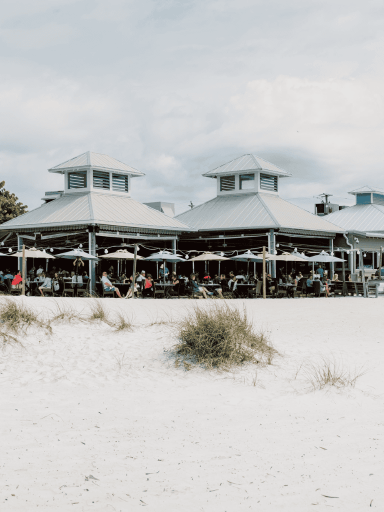 Beachside restaurant with outdoor seating and umbrellas, perfect for seaside dining experiences.