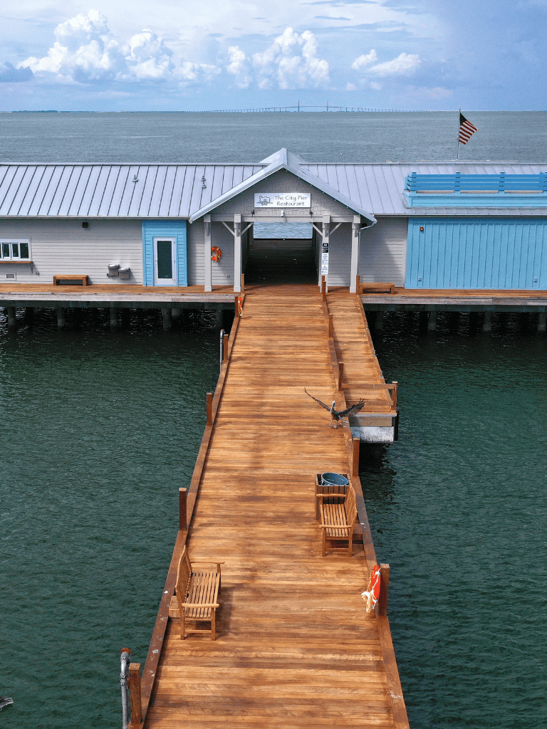 Fishing pier on the water leading to The City Pier Restaurant with seating and scenic views.