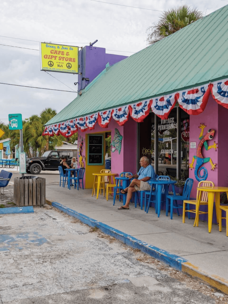 Colorful vintage cafe with outdoor seating in a tropical area, decorated with patriotic bunting.