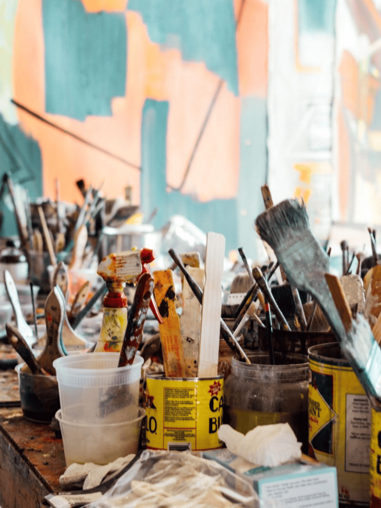 Colorful artist paintbrushes and supplies in an art studio workspace.