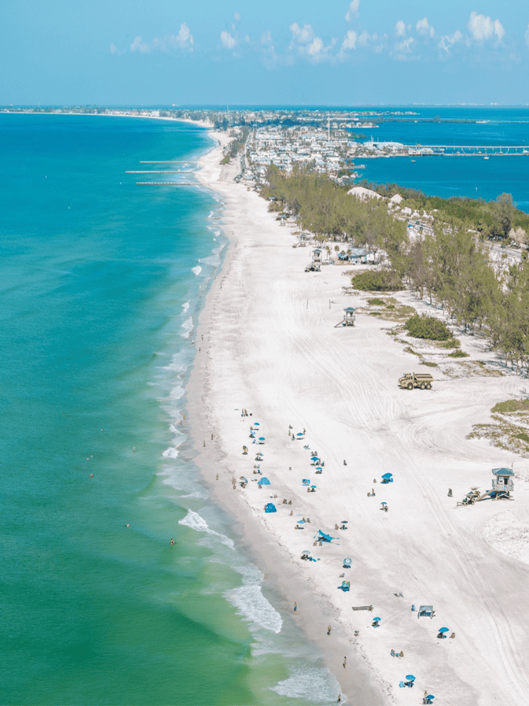 Sunny Florida beach coastline with white sand and clear turquoise waters, popular for leisure and outdoor activities.