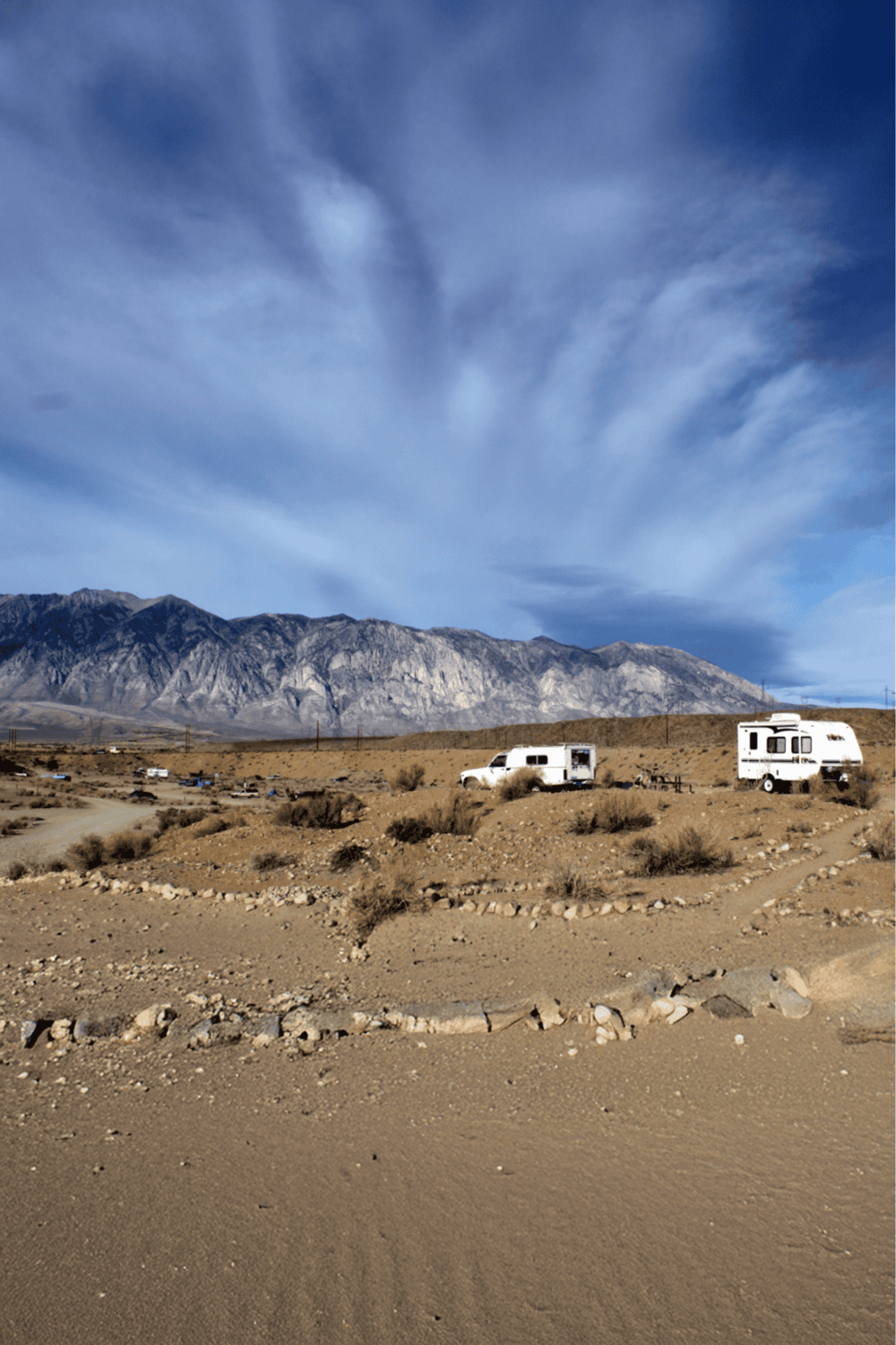 Remote desert RV camping with mountain backdrop, QuestForDirections travel adventure, outdoor exploration, wilderness getaway, off-grid RV park.
