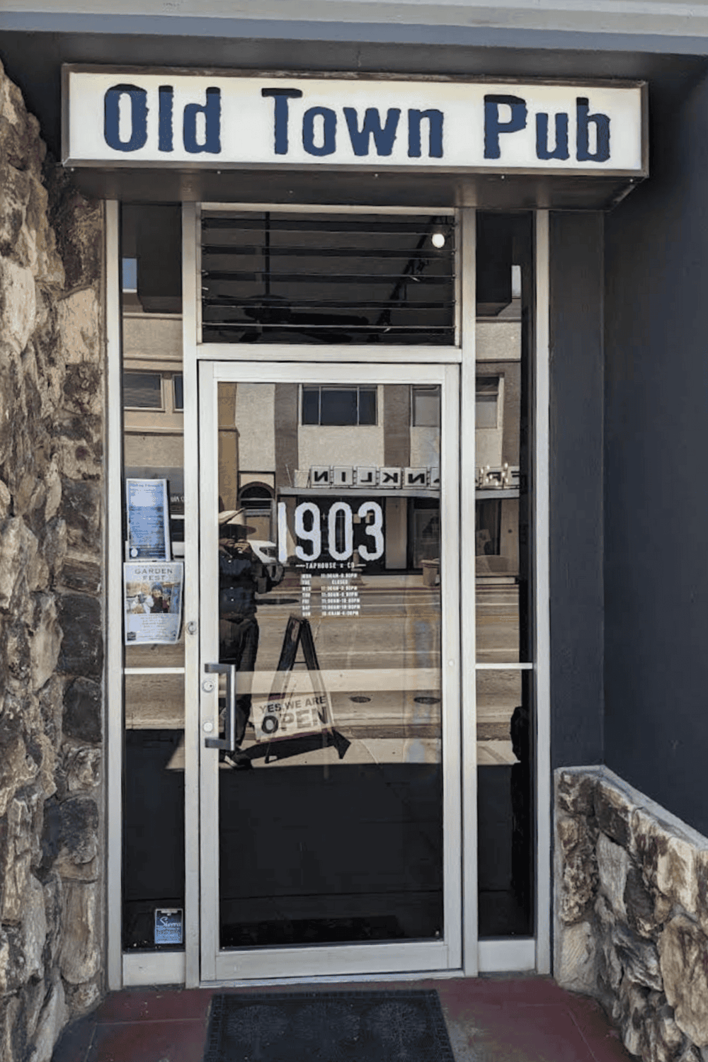 Vintage Old Town Pub entrance with modern glass door, reflecting historic architecture, cozy atmosphere for socializing and nightlife.