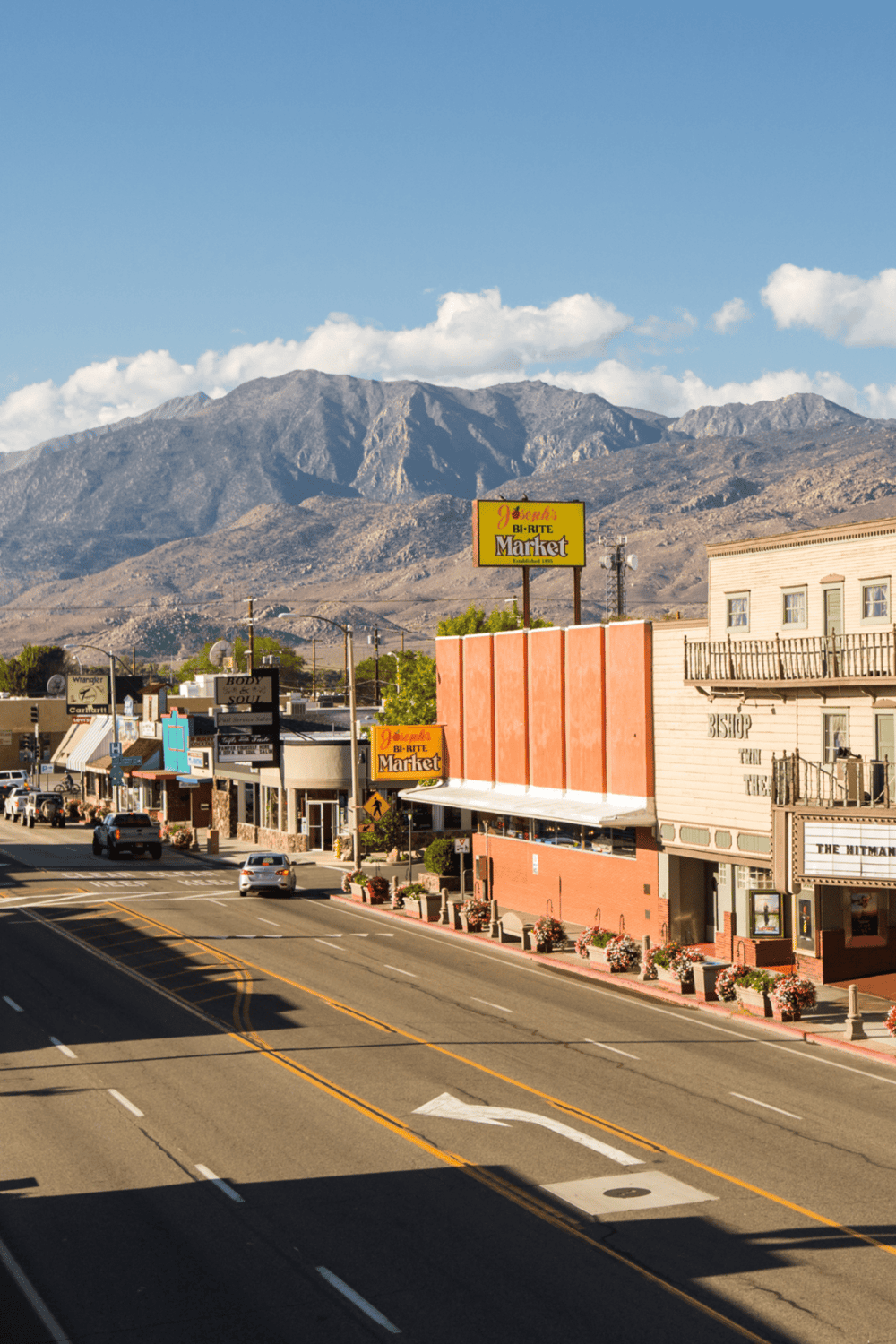 Colorful small-town street with mountains in background, featuring local shops and QuestForDirections signage.