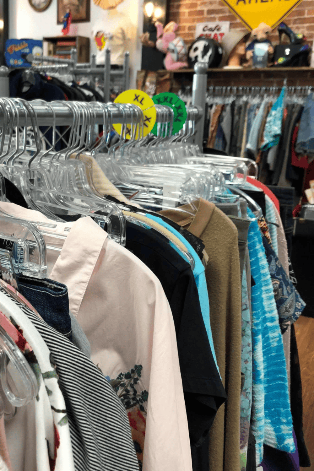 Clothing rack with assorted colorful shirts and jackets at thrift store or secondhand shop.