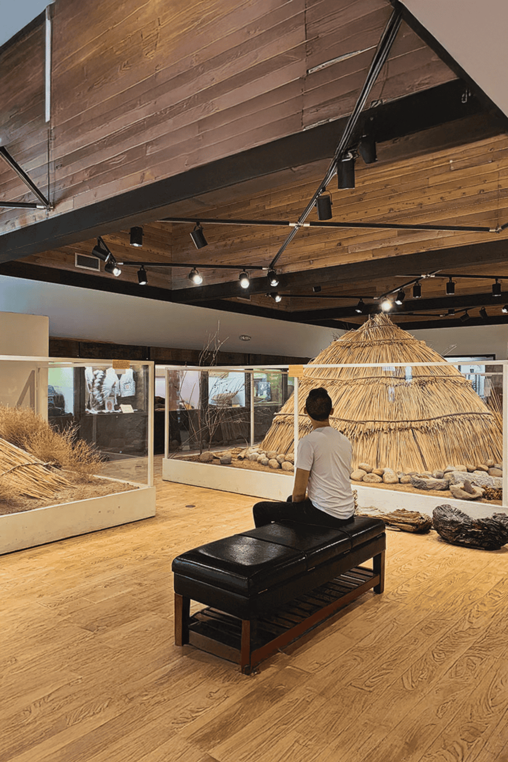 1. Indoor museum exhibit with traditional huts and dried grass displays.