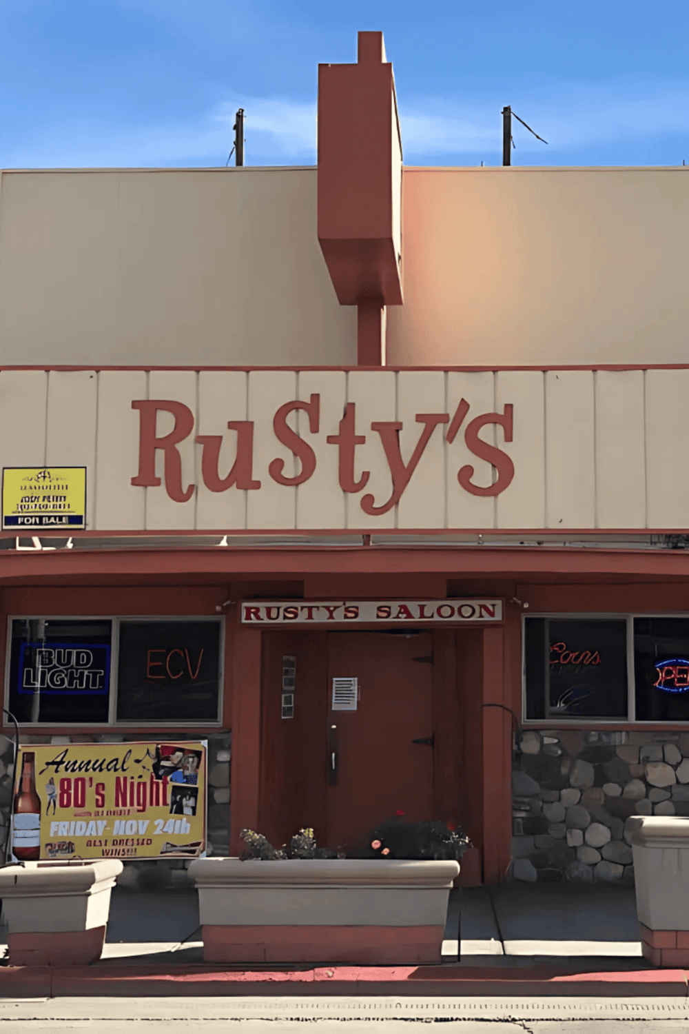 Rusty's Saloon and Bar exterior front view, featuring vintage signage and neon lights, located in a lively neighborhood.