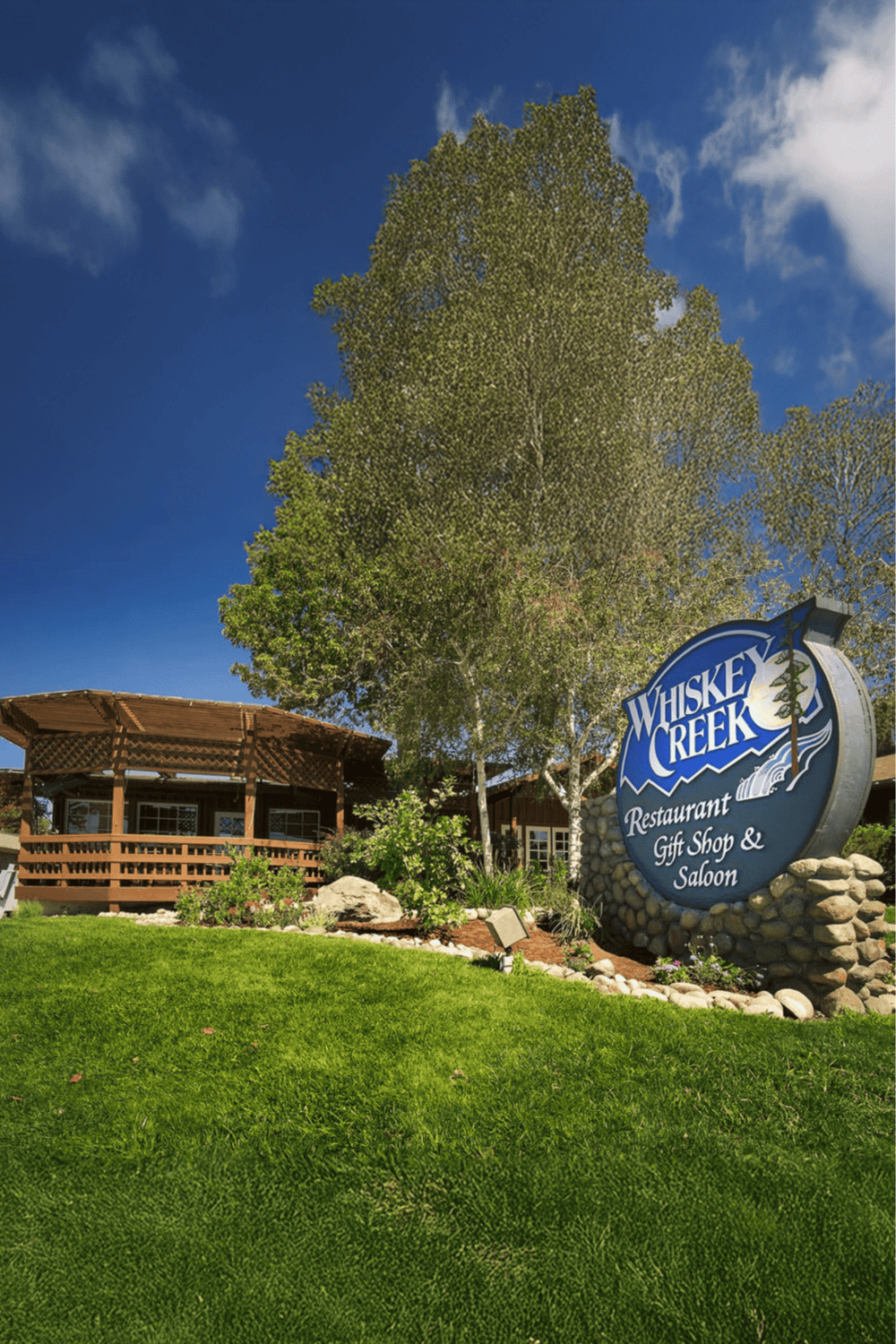 Lush green landscape outside Whiskey Creek restaurant and gift shop with clear blue sky.