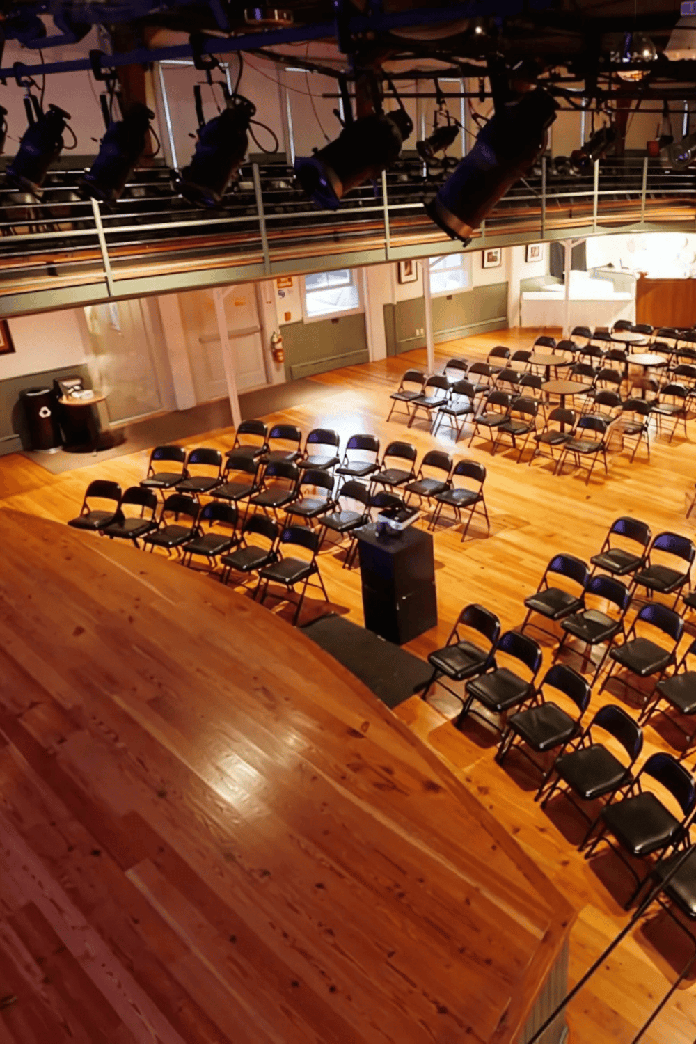 Bright, spacious event hall with tiered seating and stage, perfect for conferences and performances.