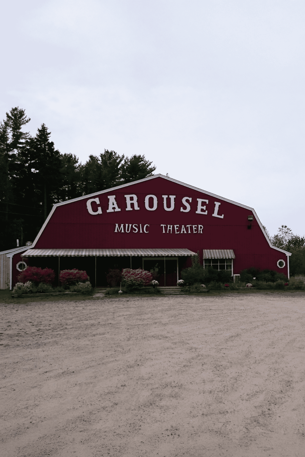 Old-fashioned red carousel music theater building with surrounding greenery and gravel foreground.