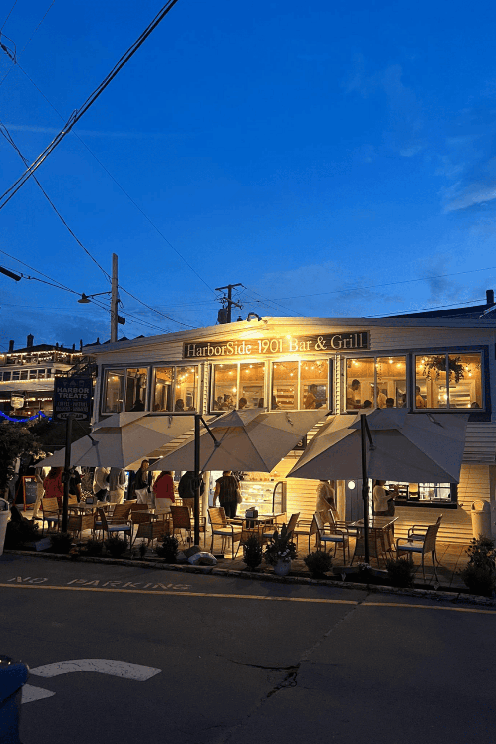 Cozy waterfront restaurant at night with outdoor seating and warm lighting, showcasing local dining experience at HarborSide 1901.