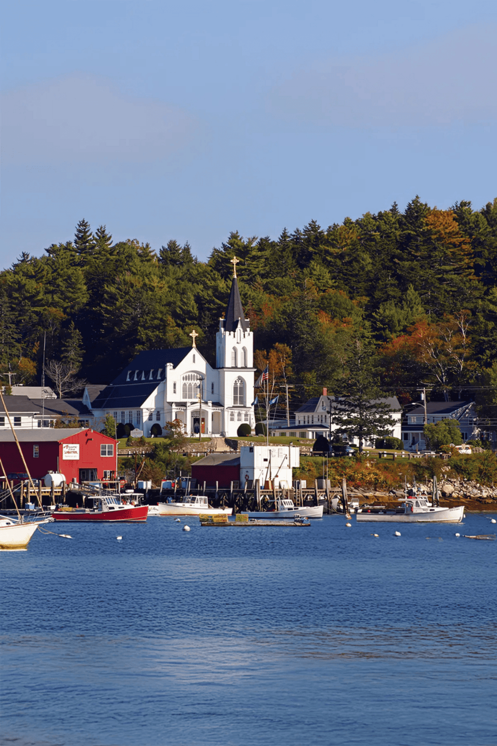 Charming coastal town with a white church, colorful buildings, and boats docked on the water. Perfect for scenic travel and waterfront adventures.
