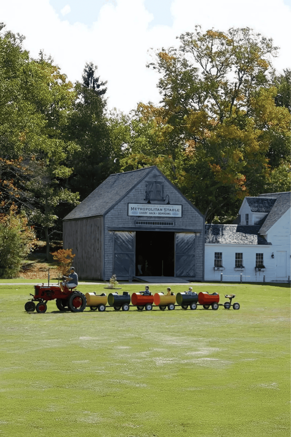 Colorful miniature train ride at Metropolitan Stable with scenic autumn trees in the background.