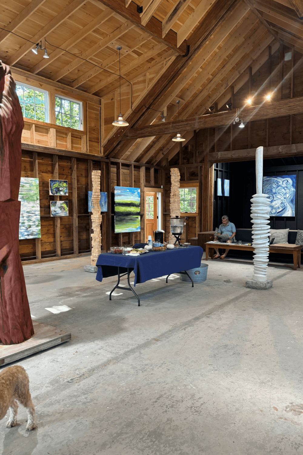 Colorful abstract art displayed in a rustic wooden art gallery with high vaulted ceilings and natural light.
