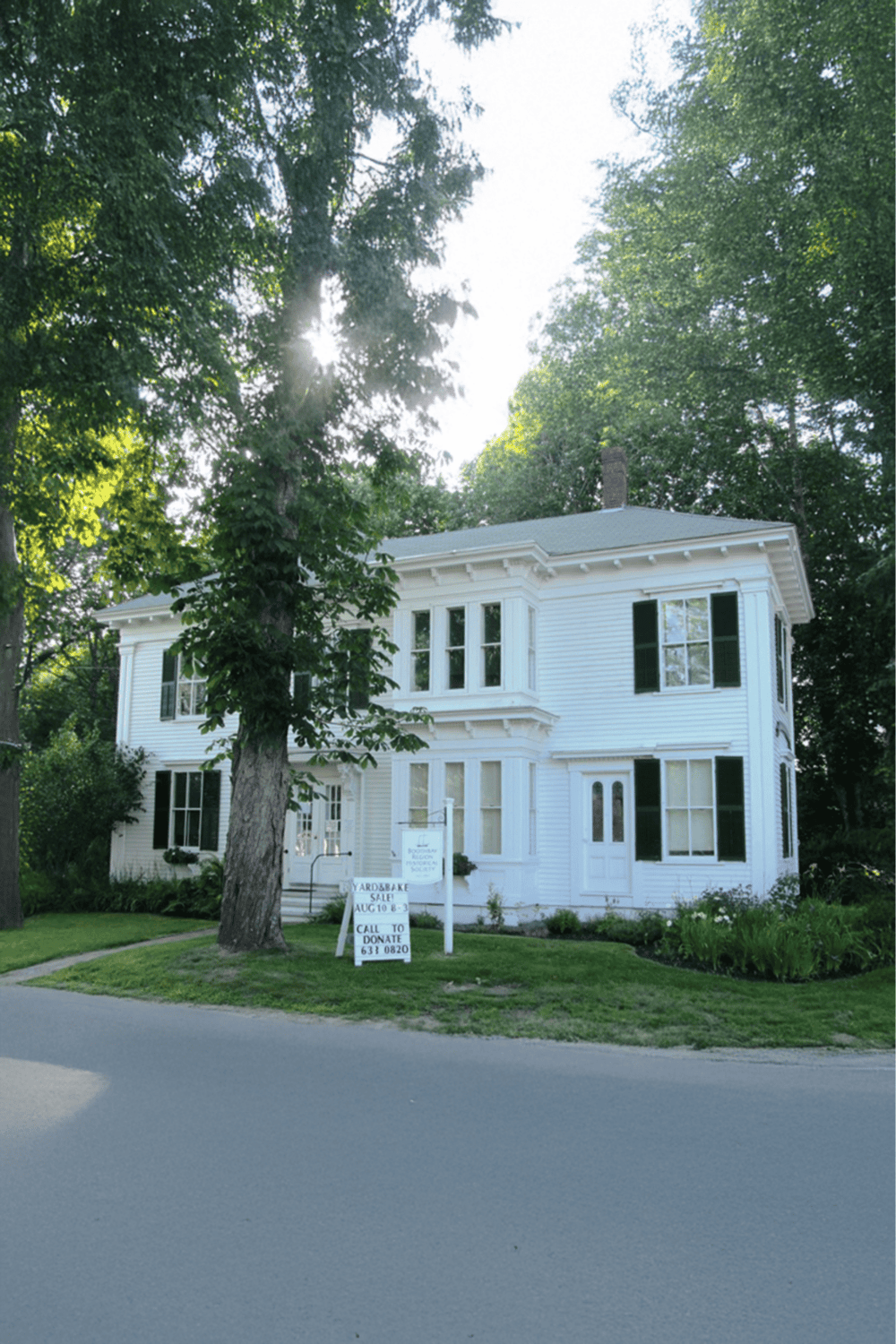 Colorful house with yard sale sign in a lush, wooded neighborhood, perfect for community engagement and local directions.