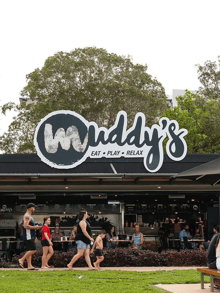 Family dining at Muddy's restaurant with outdoor seating, casual atmosphere, and diverse guests.