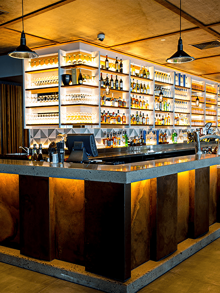 Modern bar with illuminated liquor shelves and cozy warm lighting for a vibrant nightlife experience.