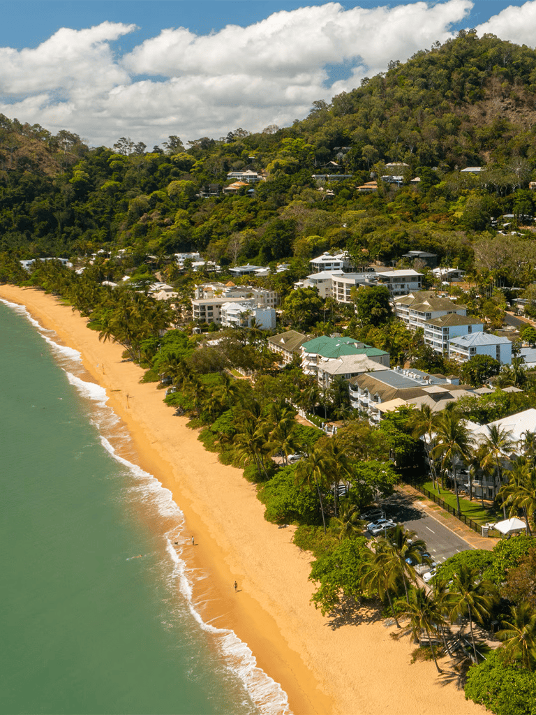 Luxurious beachfront homes with scenic ocean views and lush green hillside surroundings.