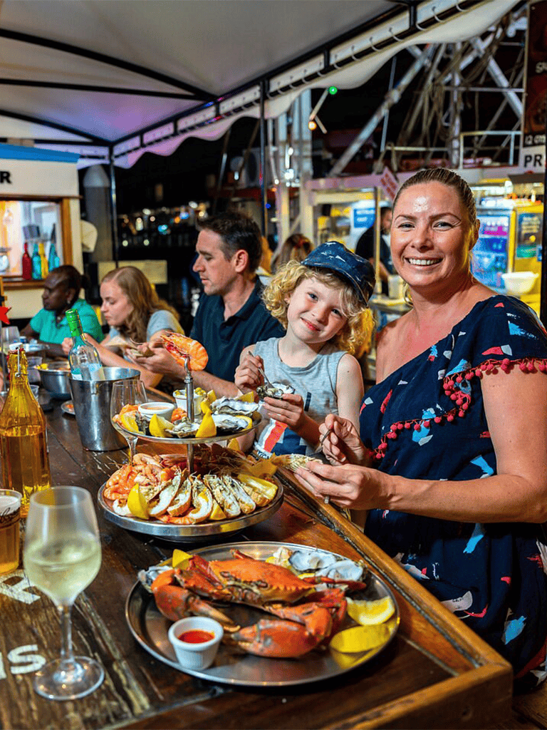 Fresh seafood dinner at a lively outdoor restaurant with family enjoying delicious lobster and shellfish.
