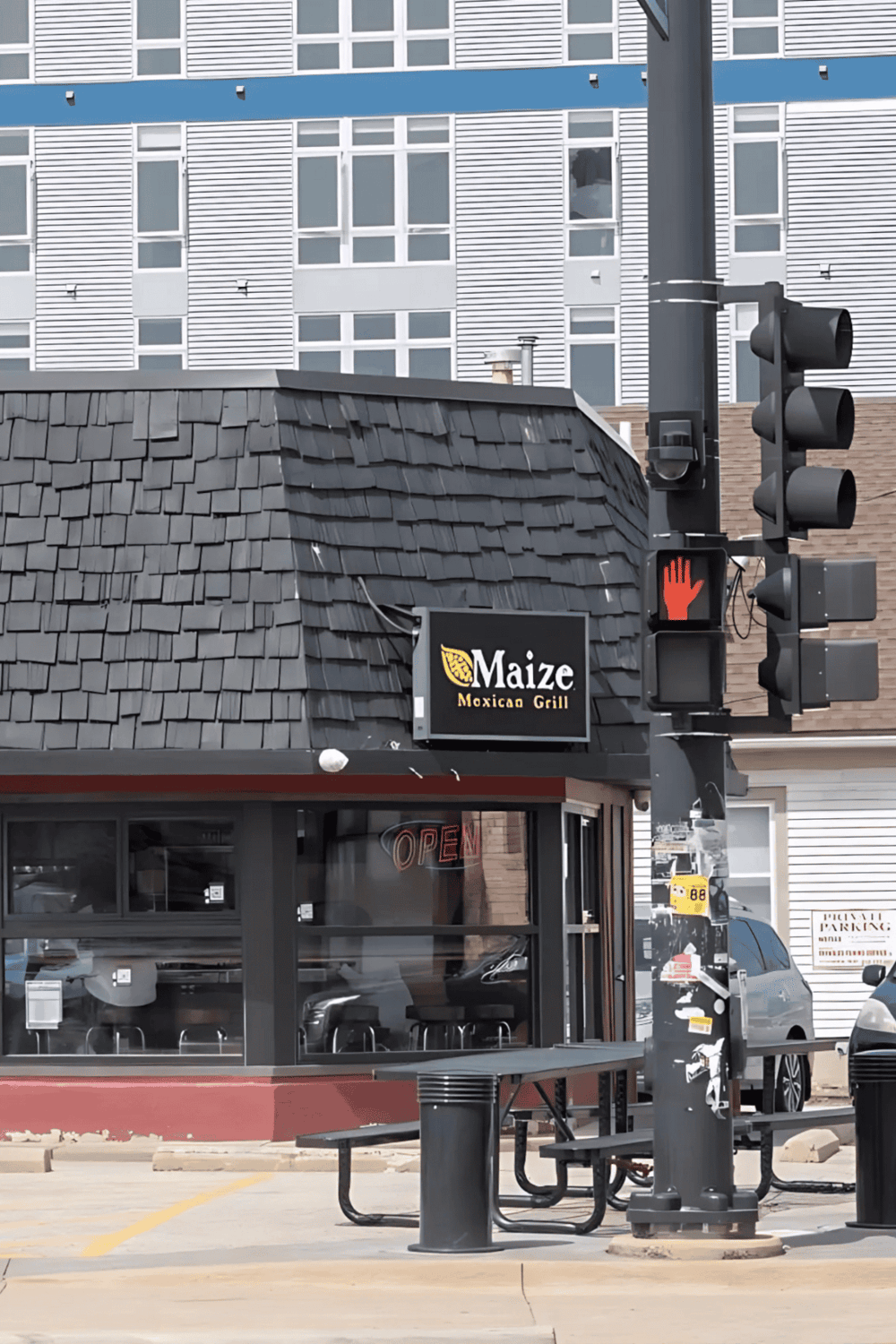 Wheelchair stop signal outside Maize Mexican Grill, urban setting with modern building background, digital signage, & outdoor seating.