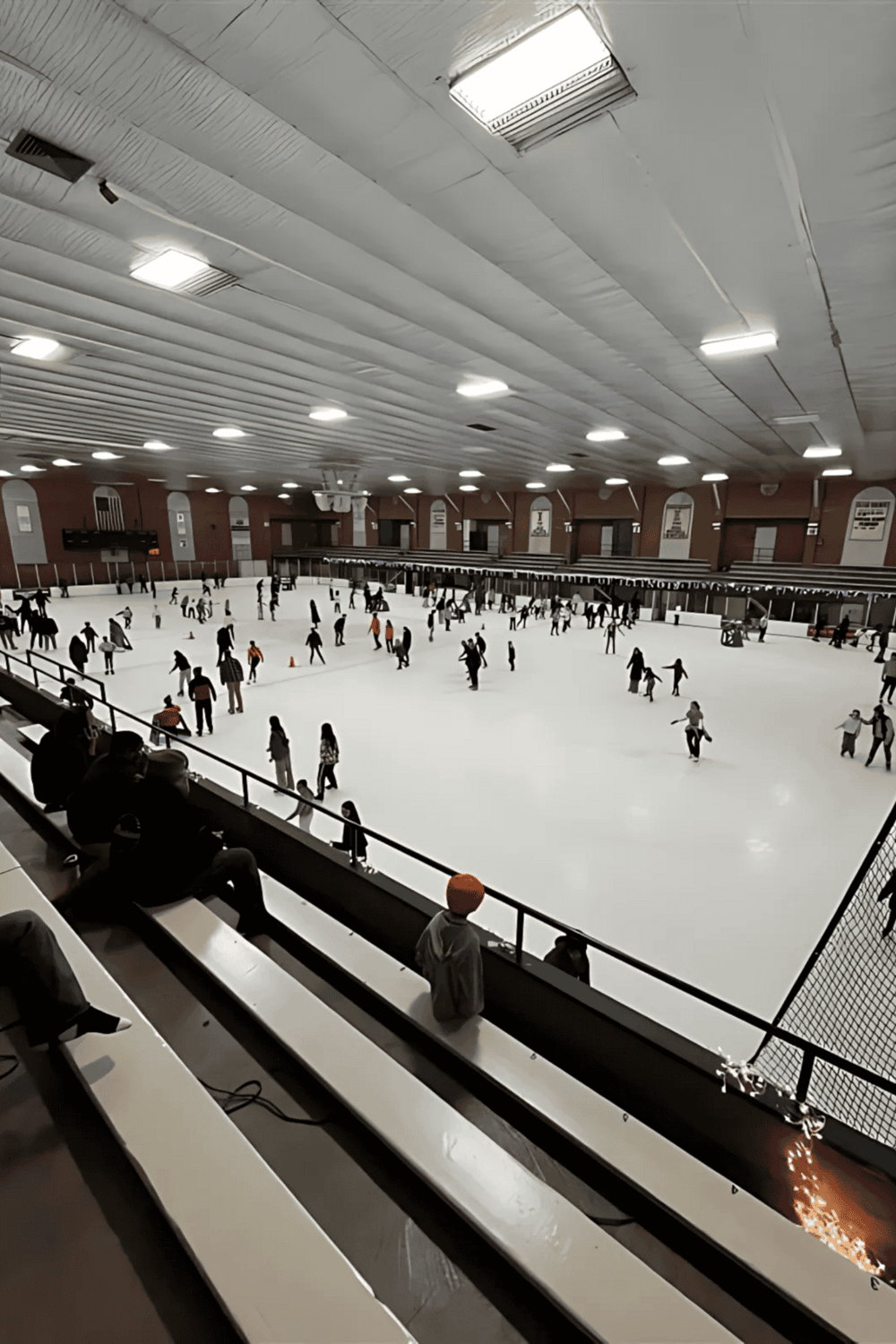 Indoor ice skating rink with people enjoying the activity. Family and friends skating, having fun, and socializing in a large, well-lit facility.