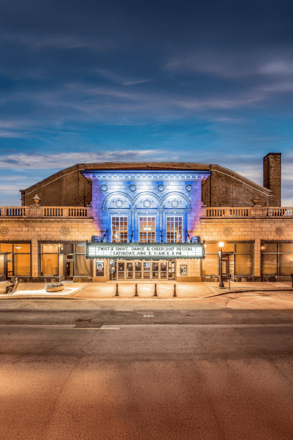 Colorfully lit historic theater facade with event marquee and nighttime sky.