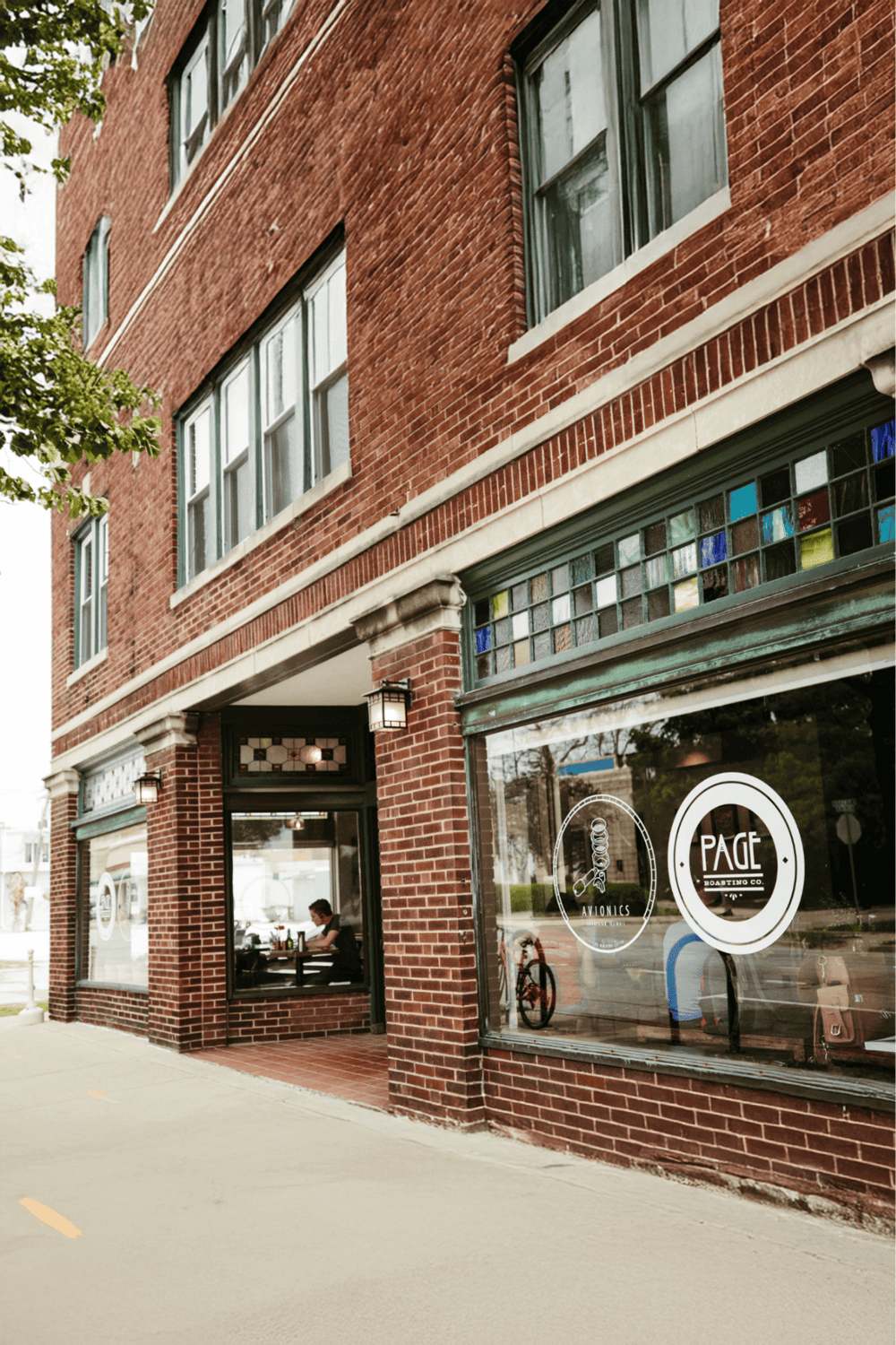 1. Cozy coffee shop on a brick building with colorful stained glass windows and outdoor seating.