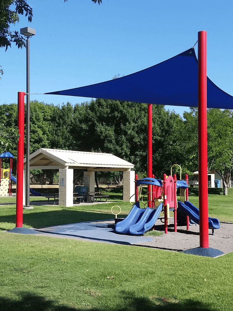 Colorful playground with slides and shade sails at Quest for Directions park.