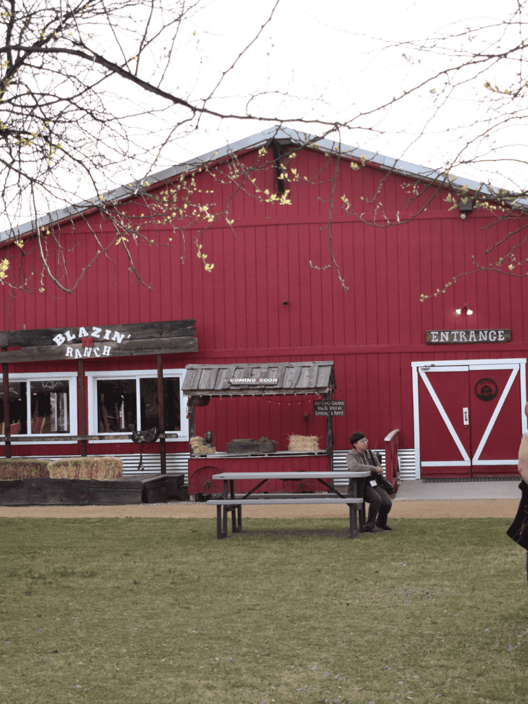 Red barn with "Blazin' Ranch" sign, entrance door, and outdoor seating area.
