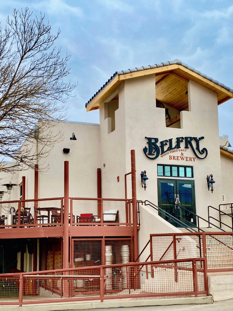 Stylish brewery building with outdoor seating and brewery barrels, modern design for a welcoming atmosphere.