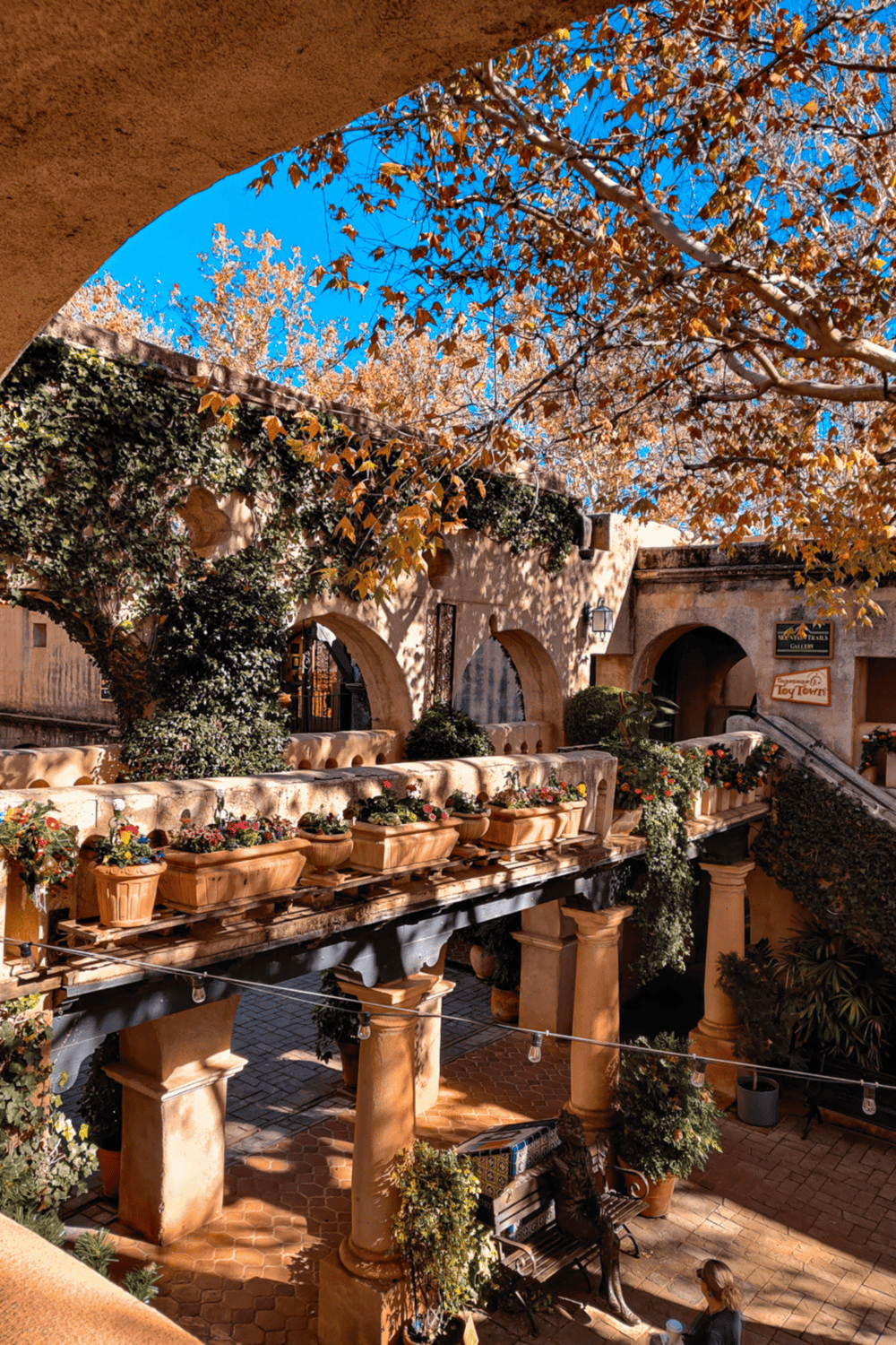 Charming Mediterranean-style courtyard with flowers, archways, and cozy seating. Perfect for outdoor dining and relaxation at QuestForDirections.