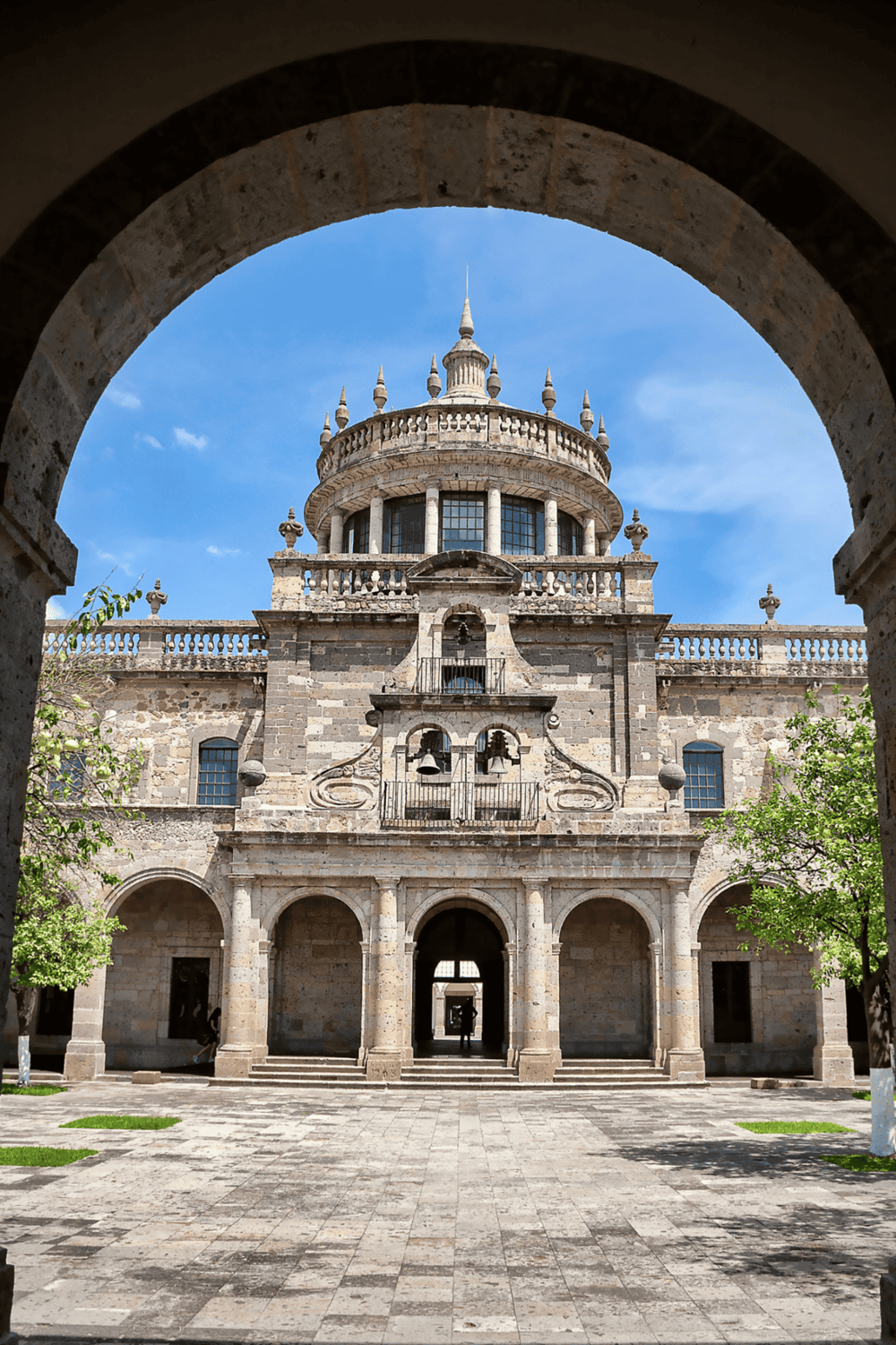 Ancient castle viewed through stone archway, historic architecture with towers and bell features.