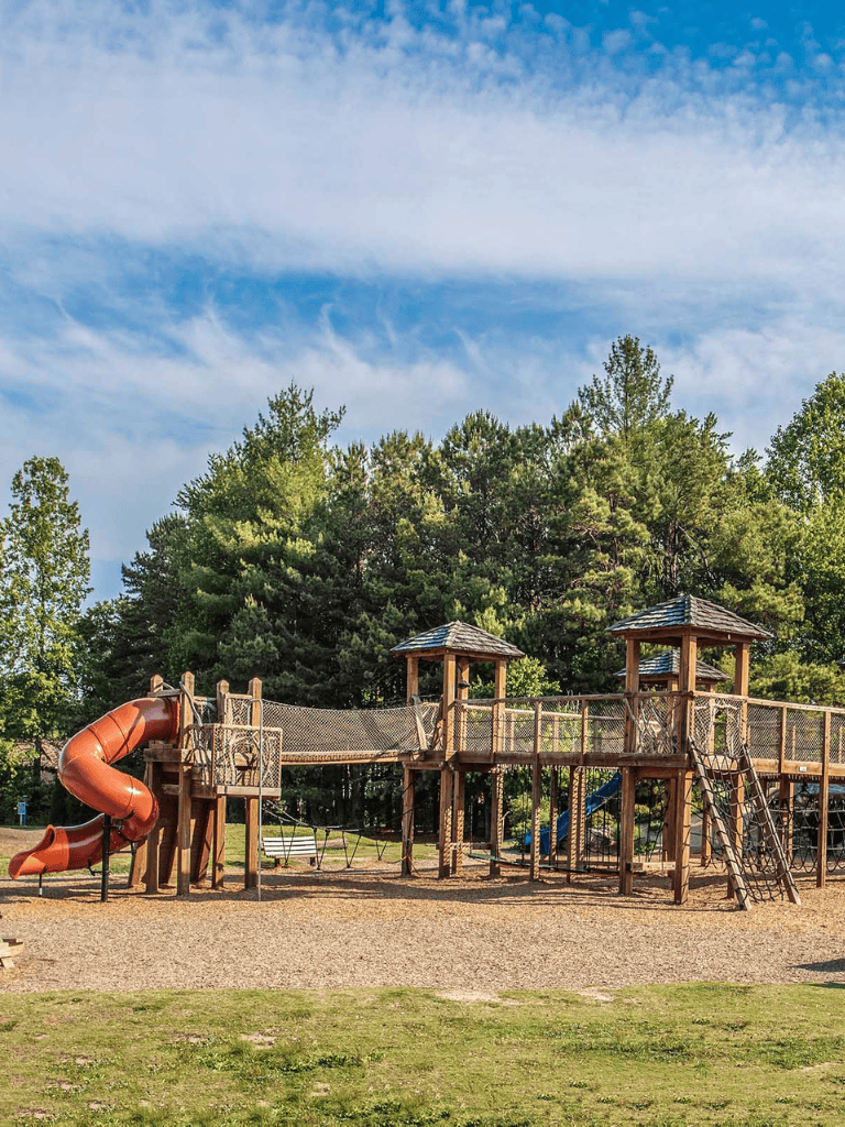 Colorful playground structure with slides and climbing areas in a park setting.