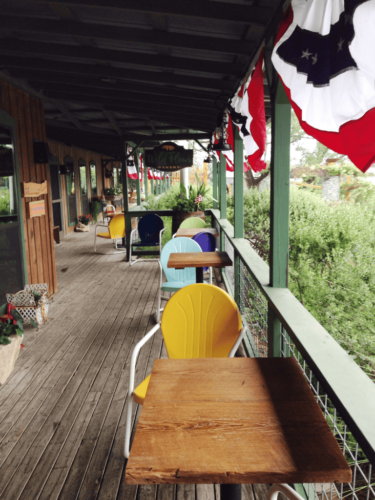 Bright outdoor bakery terrace with colorful chairs and patriotic flags for a welcoming dining experience.