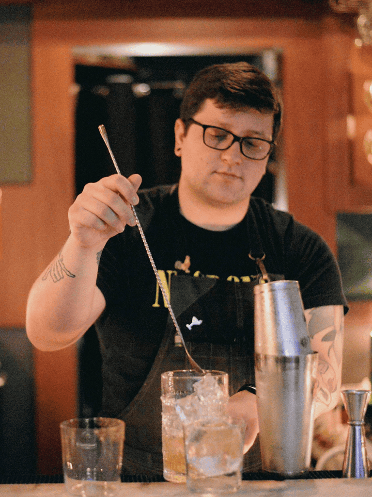 Mixed drinks bartender preparing cocktail at bar, professional mixology, nightlife bar entertainment.