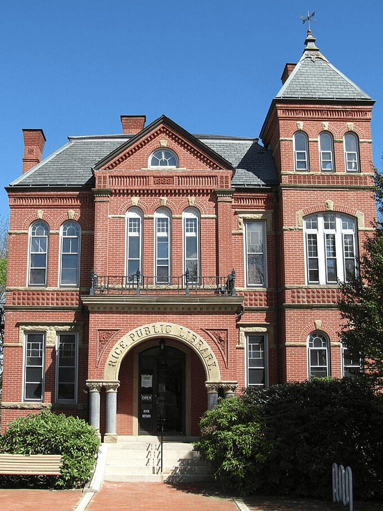 Historic brick city hall building with a clock tower and arched entrance in downtown area.