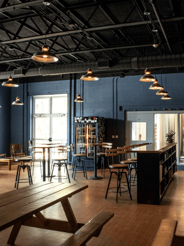 Bright modern coffee shop interior with high ceilings and industrial lighting, perfect for relaxation and socializing.