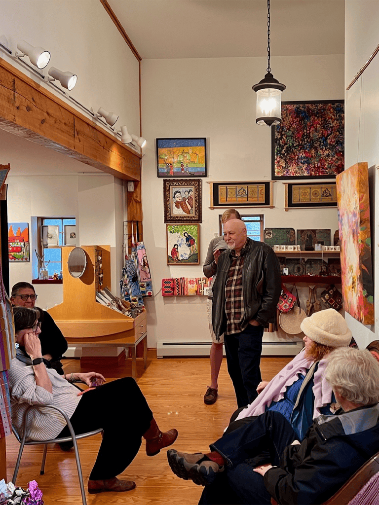 Colorful art gallery showcasing vibrant paintings and sculptures with visitors engaging in an art discussion.