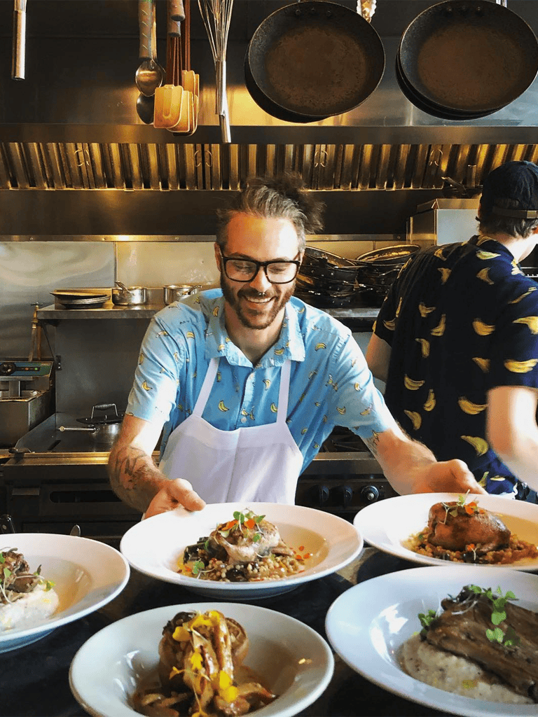 Delicious gourmet dishes served in a professional kitchen with smiling chef, food presentation, fine dining atmosphere.