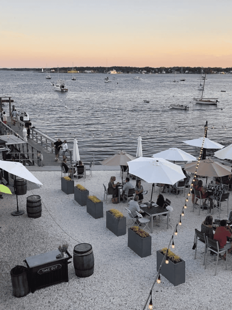 Boats on water at waterfront restaurant with outdoor dining and scenic harbor view.