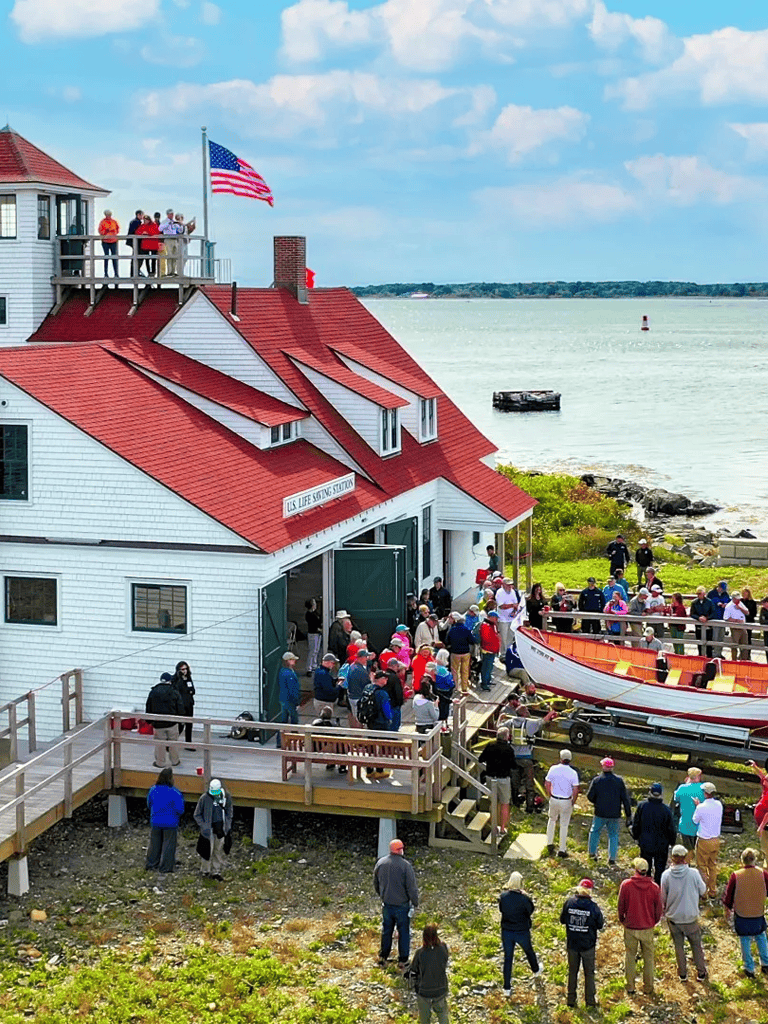 Historic lighthouse with people visiting and scenic water views, coastal destination for tours and sightseeing, Atlantic Ocean shoreline.