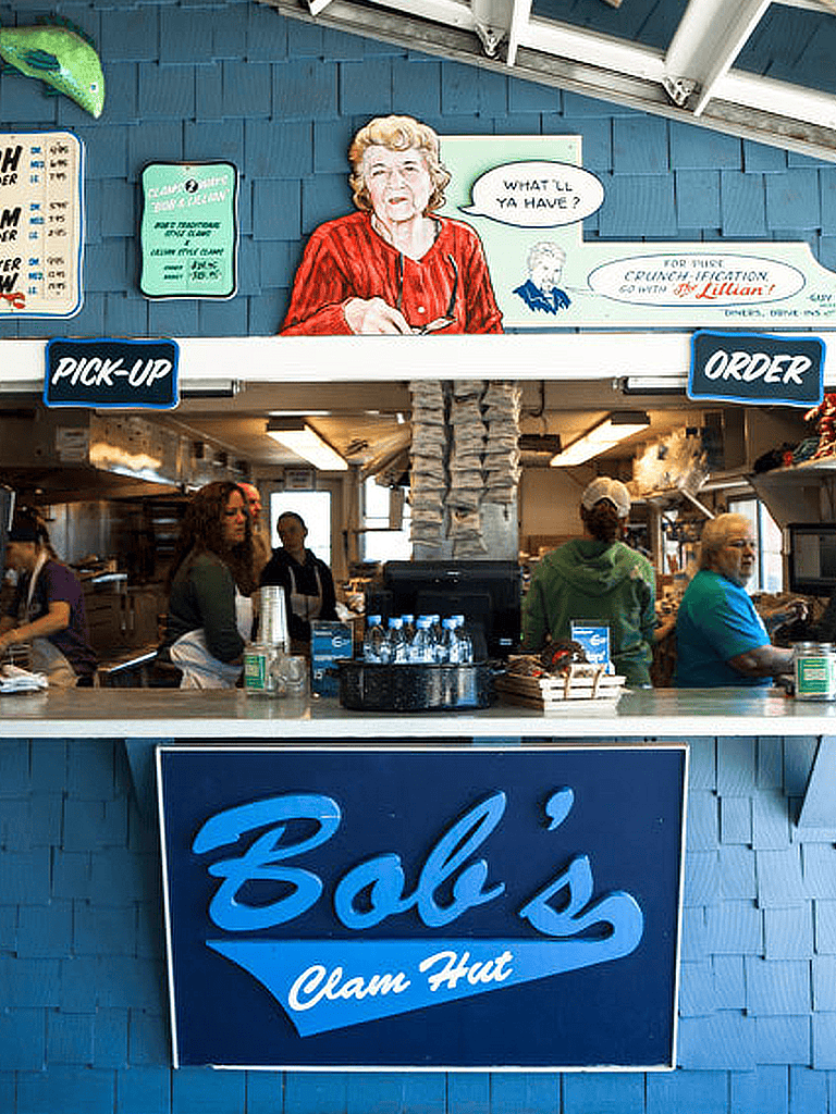 Vintage clam hut counter with "Pick-up" and "Order" signs at Bob's Clam Hut, bustling with staff and customers.