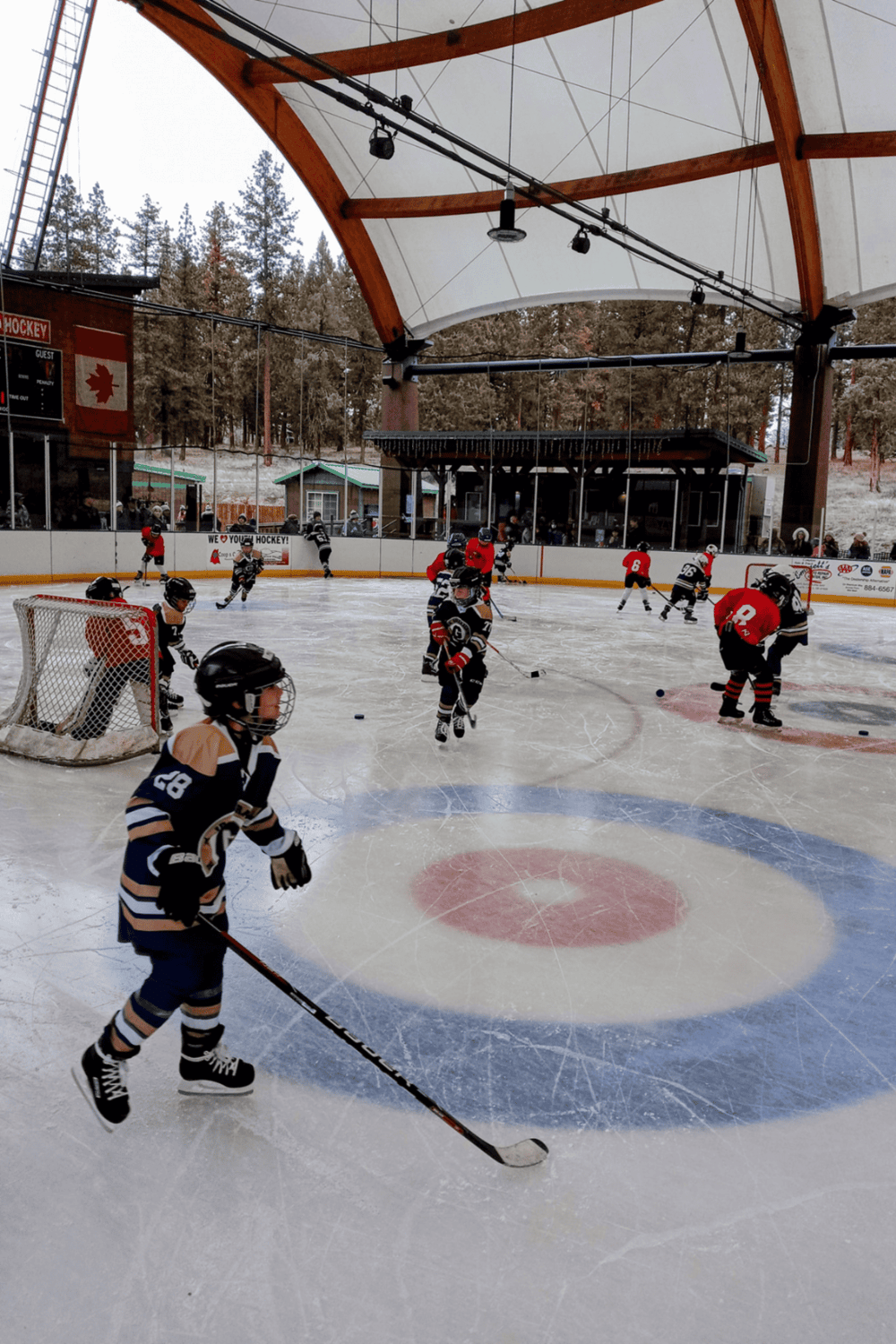 Kids hockey game at indoor ice rink in a scenic outdoor mountain setting, perfect for youth sports and family activities.