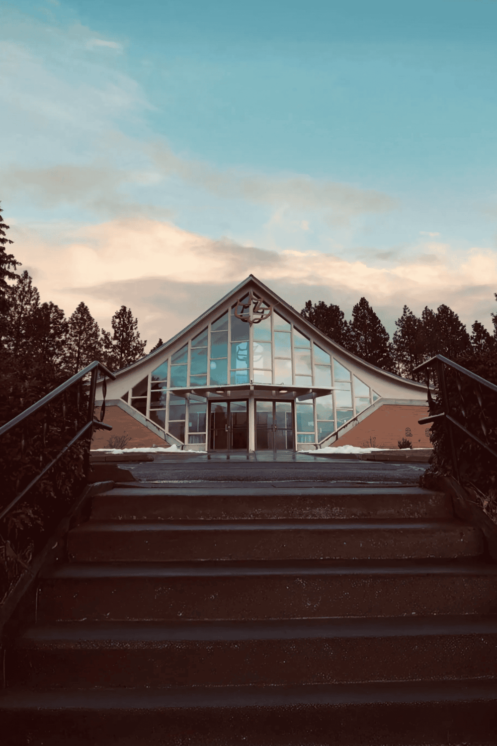 Modern church building with glass facade and surrounding trees, ideal for community worship and spiritual gatherings.