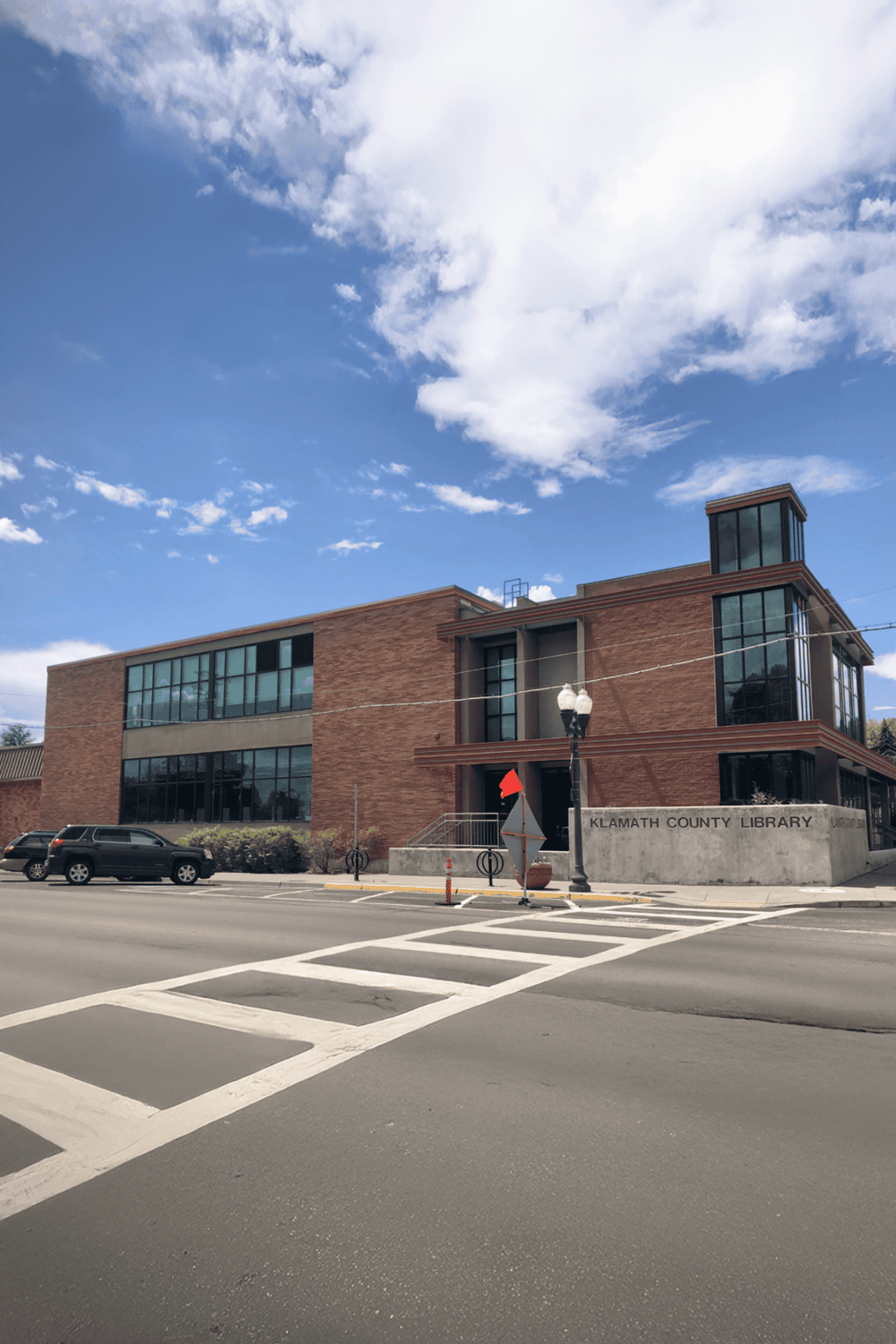 Modern brick County Library building with large glass windows in a downtown area.
