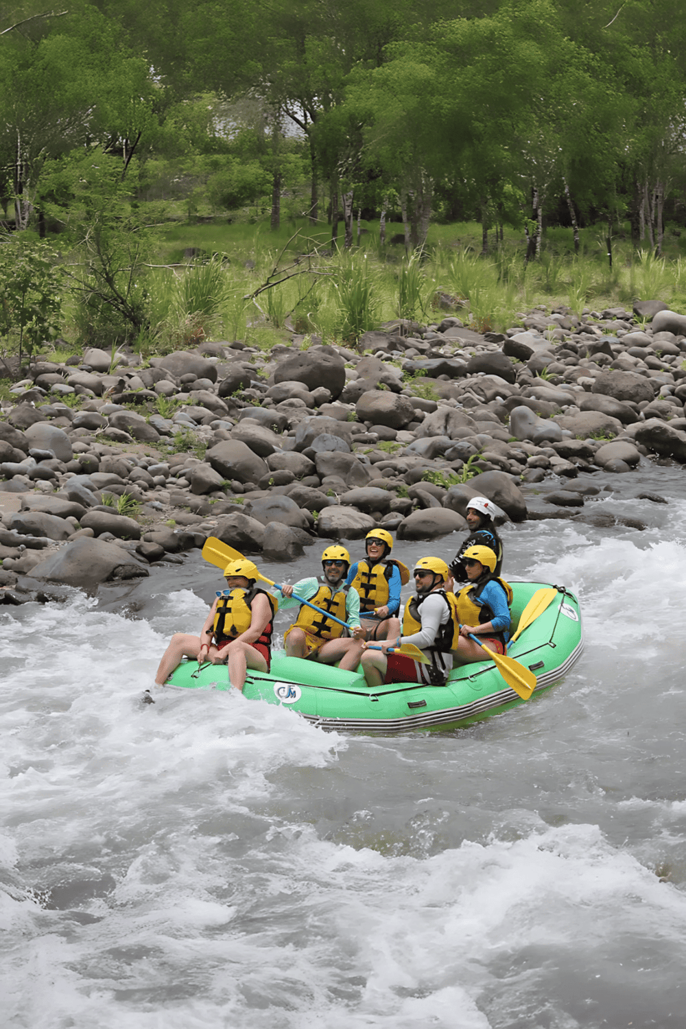 Excursion rafting adventure on a river with lush green scenery and rocky banks.