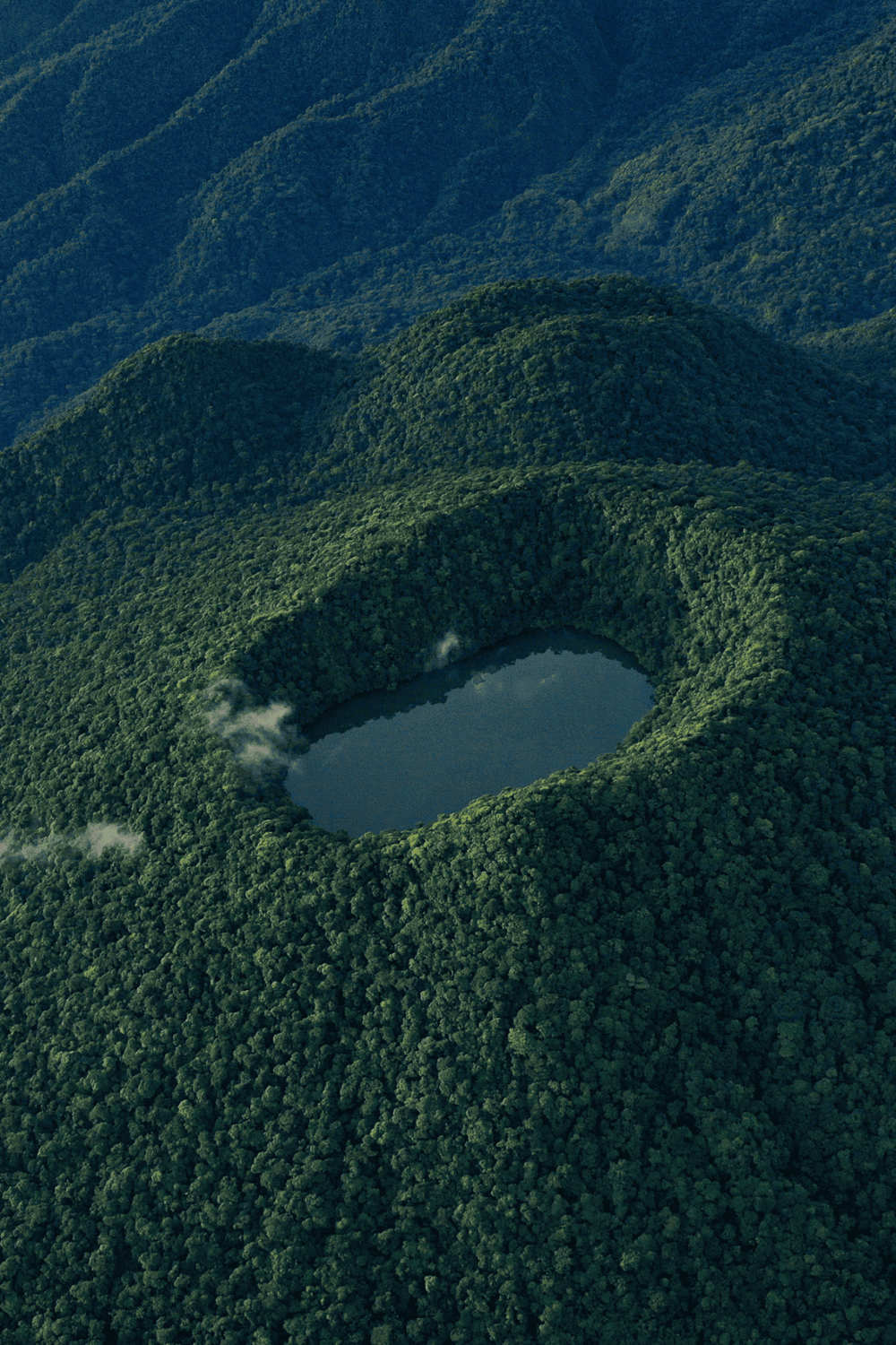 Lush green mountains surrounding a volcanic crater lake, created by a natural volcanic erosion process.