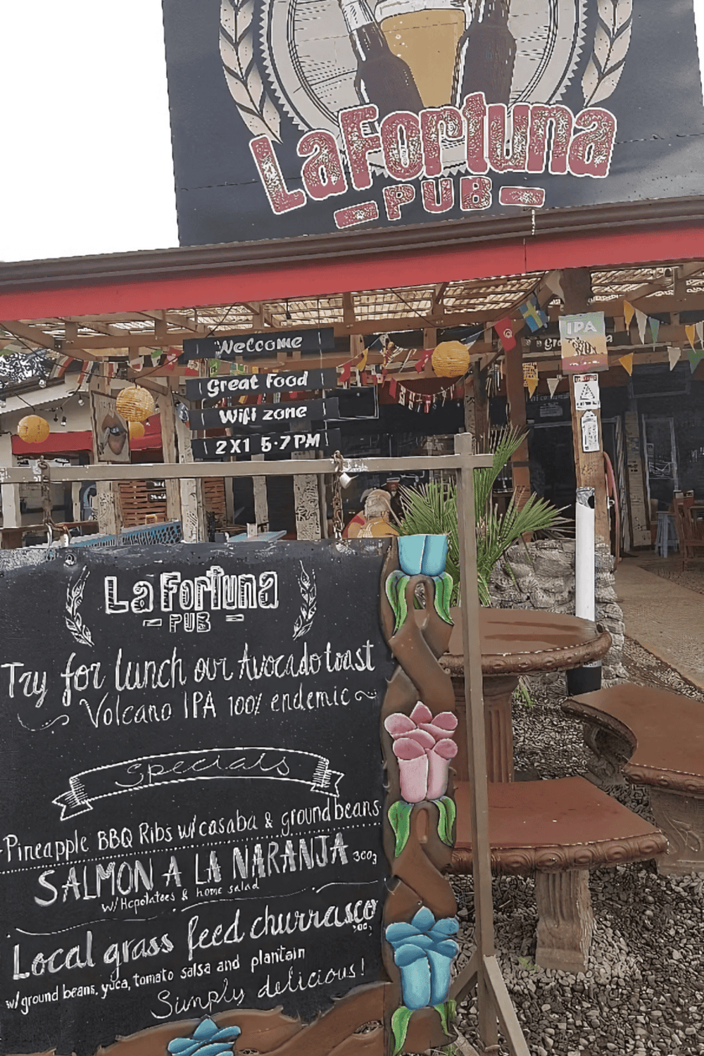 Enjoy delicious Ecuadorian food at La Fortuna Pub with outdoor seating and vibrant tropical decor.