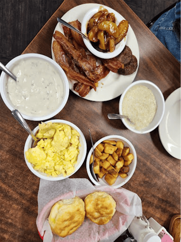 Savory Southern-style breakfast with bacon, eggs, grits, roasted potatoes, biscuits, and gravy.